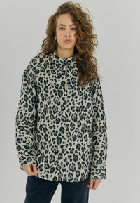 Leopardprint skjorte med knaplukning i lys grå og sort, lange ærmer, afslappet pasform, med en frontlomme og klassisk krave.
