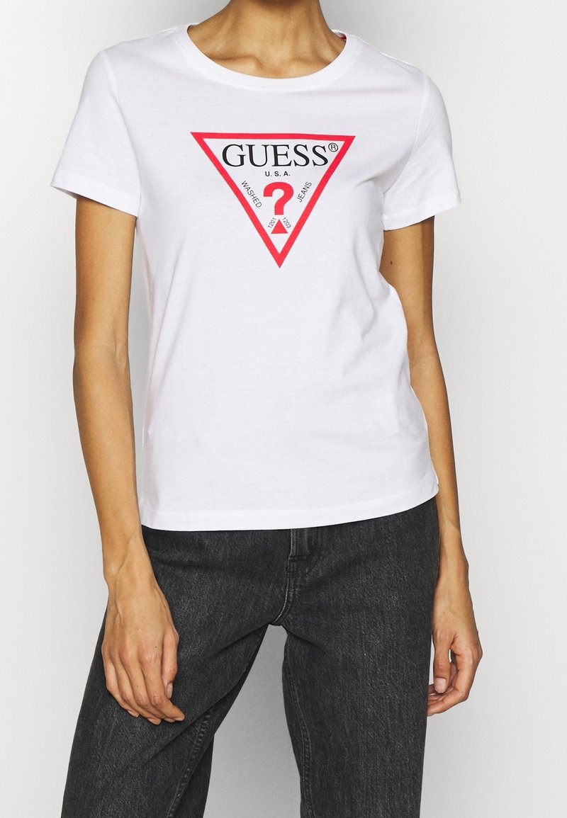 T-shirt en coton blanc avec col rond, arborant un graphique triangulaire rouge incluant le texte "GUESS® U.S.A." et un point d'interrogation au centre.