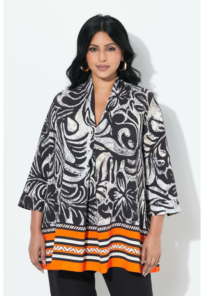 Zwart-witte tuniek met bloemmotief, driekwart mouwen en een oranje gestreepte zoom. Gemaakt van lichtgewicht stof met een losse pasvorm.