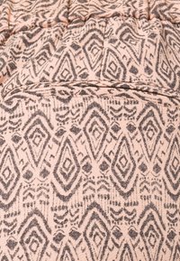 Světle růžová látka s geometrickým černým a šedým diamantovým vzorem, s jemnou strukturou a elastickým páskem, včetně malé kapsy.