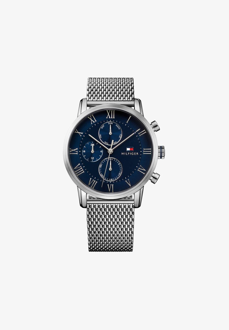 Zegarek chronograf w srebrnym odcieniu z granatową tarczą, srebrnymi cyframi rzymskimi i stalową siateczkową bransoletą. Posiada trzy subtarcze.