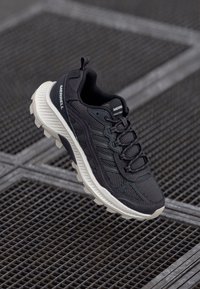 Schwarzer Sportschuh mit Obermaterial aus Mesh, strukturierten Akzenten und einer massiven weißen Sohle. Verfügt über Schnürsenkel und eine markierte Zunge für einen sicheren Sitz.