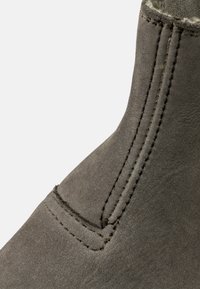 Botină gri din suede, cu glezna înaltă, detalii de coasere vizibile și o textură netedă. Nu există elemente metalice sau modele.