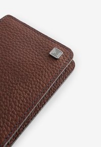 Braune Lederbrieftasche mit strukturiertem Finish, blauen Nähten und einem quadratischen metallischen Akzent in der Ecke. Schlankes, rechteckiges Design.