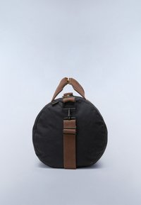 Ronde zwarte duffeltas met bruine verstelbare schouderband en korte draaggrepen tegen een effen lichtgrijze achtergrond.
