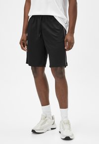 Sorte athletic shorts med elastisk talje og snøre. Fremstillet af letvægtsmateriale, med sidelommer og en afslappet pasform.