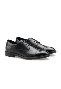 Chaussures de ville noires en cuir avec une finition lisse, bout arrondi et détails de couture subtils. Présentent un design à lacets et une semelle en caoutchouc.