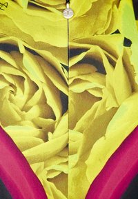 Tissu à motifs floraux présentant des roses jaunes avec des nuances de vert et des accents de rose. Texture lisse avec une couture centrale et des éléments en métal.