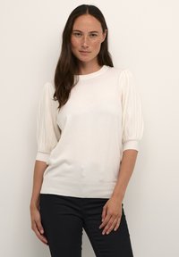 Pull en tricot blanc avec de courtes manches bouffantes côtelées, un col rond et un ourlet ajusté. Texture douce, tissu léger.
