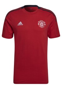 Camiseta de algodón roja con mangas cortas, cuello redondo, con acentos negros en los hombros y el logo del Manchester United en el lado izquierdo del pecho.