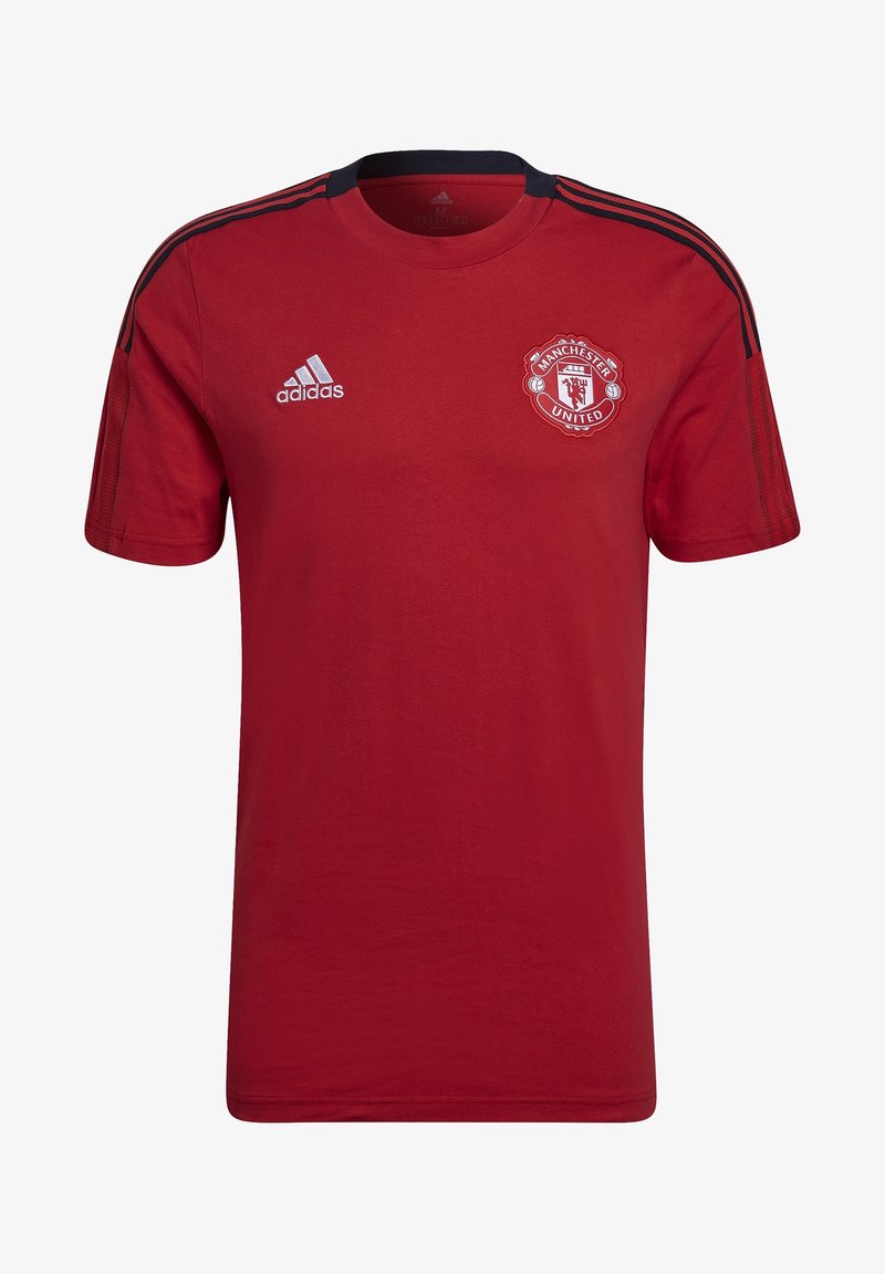 Camiseta de algodón roja con mangas cortas, cuello redondo, con acentos negros en los hombros y el logo del Manchester United en el lado izquierdo del pecho.