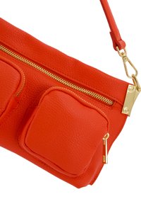 Rote Lederhandtasche mit strukturierten Oberflächen, goldenen Beschlägen und zwei äußeren Reißverschlusstaschen. Verstellbarer Trageriemen für vielseitige Tragemöglichkeiten.