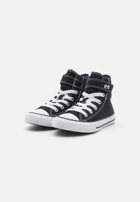 Zapatos deportivos altos de lona negra con suelas de goma blanca, diseño de cordones y una correa de velcro. Presentan costuras blancas y acentos de logotipo.