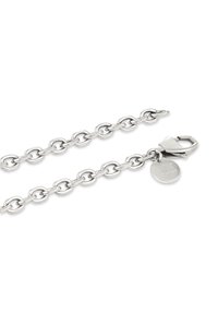 Collana a catena d'argento con maglie ovali, chiusura sicura e una targhetta circolare con la scritta "Studios". Texture liscia con finitura metallica.