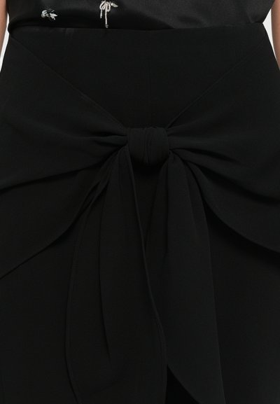 Zwarte rok met een opvallende strikdetail bij de taille, gemaakt van een gladde stof met een gestructureerd ontwerp en gelaagde plooien.