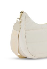 Sac à main beige matelassé avec une forme incurvée, quincaillerie dorée et une bandoulière avec le mot "MARLY" en relief. Texture lisse et design minimal.