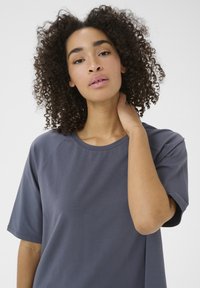 T-shirt grigio a maniche corte con scollatura rotonda e tessuto morbido, caratterizzato da maniche raglan e una vestibilità rilassata. Texture liscia e design semplice.