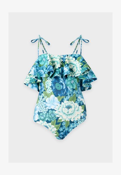 Maillot de bain une pièce bleu à motif floral avec un design à volants épaules dénudées et des bretelles à nouer sur un fond uni clair.