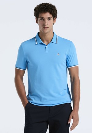 Polo-shirt bleu clair à manches courtes, avec un col blanc contrastant et des rayures aux poignets, arborant un petit logo de pingouin sur la poitrine gauche.