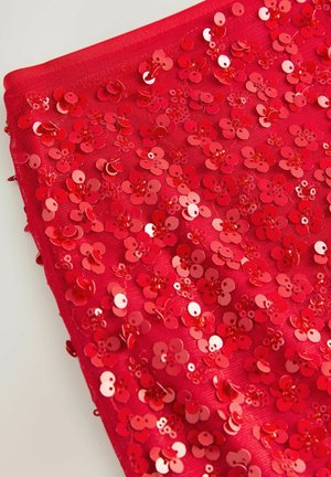Tissu rouge recouvert de sequins rouges brillants en forme de fleurs, avec des tailles et des textures variables, créant une apparence superposée et texturée.