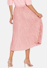 Faltender Midirock aus weichem, pinken Stoff, mit einem gerafften Bund und fließender Silhouette. Durchsichtige Textur mit dezentem Glanz.