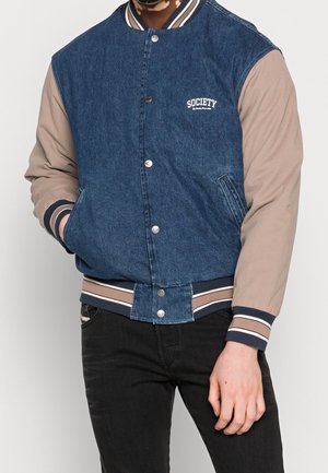 Chaqueta bomber de mezclilla con mangas beige, botones de presión y un logo de "Society". Cuenta con un cuello y puños de canalé a rayas. Bolsillos en la parte delantera.