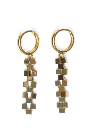 Złote kolczyki koła z wiszącymi pionowymi pasmami małych złotych kwadratowych koralików połączonych w wzór łańcuszka na białym tle.