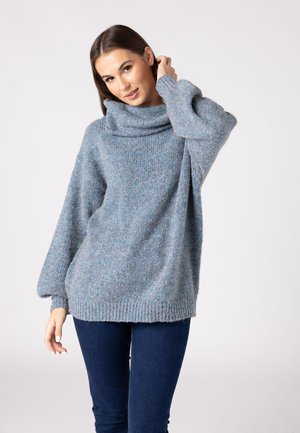 Light blue oversized sweater made of textured knit fabric. Features a cowl neck and tapered sleeves, with a ribbed hem at the bottom.