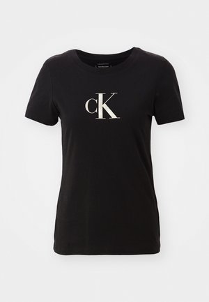 T-shirt noir à manches courtes en coton avec un col rond. Dispose d'un grand logo "cK" blanc sur le devant. Design simple, sans motifs.