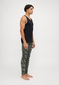 Black sleeveless tank top paired with green camo leggings. The fabric is stretchy. The leggings feature a camouflage pattern with varied green tones.