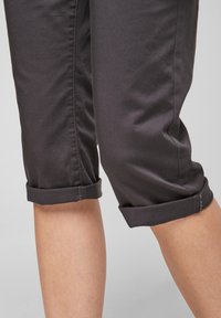Tummanharmaat lyhyet housut, jotka on valmistettu pehmeästä materiaalista. Niissä on käärityt lahkeet, sileä pinta ja slim fit -muotoilu.