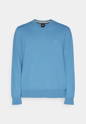 Ljust blå v-ringad tröja med ribbad textur, långa ärmar och en åtsittande midja. Har en liten logotyp på bröstet.
