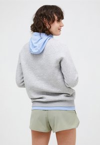 Grå bomulds hoodie med en lyseblå hætte, ribbede manchetter og kant. Båret med lysegrønne træningsshorts. Struktureret stof, afslappet pasform.