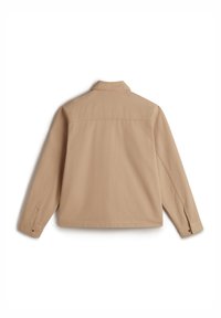 Beige canvas shirt with a collar, long sleeves, and a straight cut. Features buttoned cuffs and back yoke detailing.