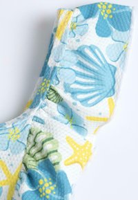 Tissu à motifs floraux présentant des couleurs bleu, jaune et vert, avec une surface texturée et des détails de couture visibles dans la couture.