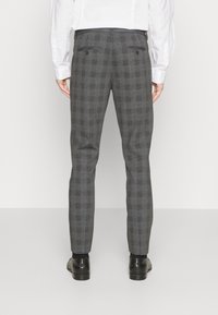 Grå rutiga byxor med slim fit, med en mjuk textur, två bakfickor och bältesloop, kombinerade med svarta skor.