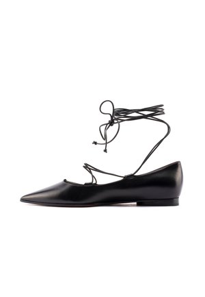Chaussure plate noire à bout pointu avec des lacets fins qui s'enroulent autour de la cheville et se nouent en un nœud, finition en cuir lisse et petit talon.