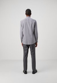 Gestreepte button-up shirt in grijs en witte katoen, met een standaard kraag en lange mouwen, gecombineerd met lichtgrijze broeken en zwarte schoenen.