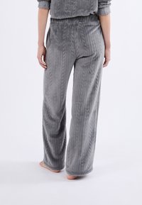 Szare, ribbedowe, welurowe spodnie dresowe o luźnym kroju. Posiadają elastyczny pas i boczne kieszenie. Miękka faktura i szeroki krój nogawki.