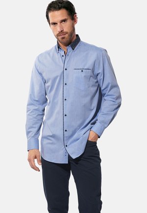 Herrenhemd aus leichtem blauen Baumwollstoff mit einem gemusterten dunkelblauen Kragen, kontrastierenden schwarzen Knöpfen und einer Brusttasche für zusätzliche Details.