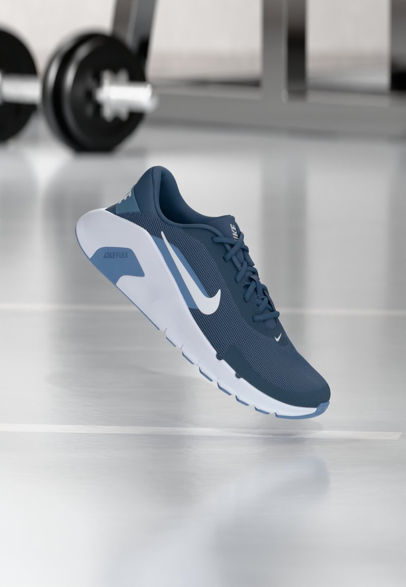 Chaussure Nike Flex bleu marine avec tige en mesh, accents blancs et semelle flexible. Elle présente un design à lacets et un bout rond.