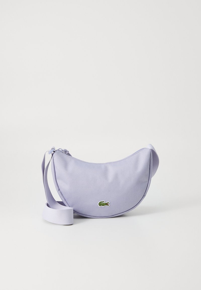 Borsa a spalla in tessuto lilla con forma curvata, chiusura con zip e logo coccodrillo ricamato verde. Tracolla regolabile per indossarla a tracolla.