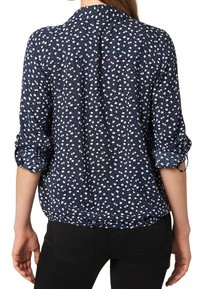 Navy blue floral blouse with white and pink patterns, button-down collar, rolled sleeves, and gathered waist design.