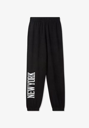 Pantaloni tuta neri con vita elastica, caratterizzati da una stampa bianca audace "NEW YORK" in verticale sulla gamba sinistra. Tessuto morbido.