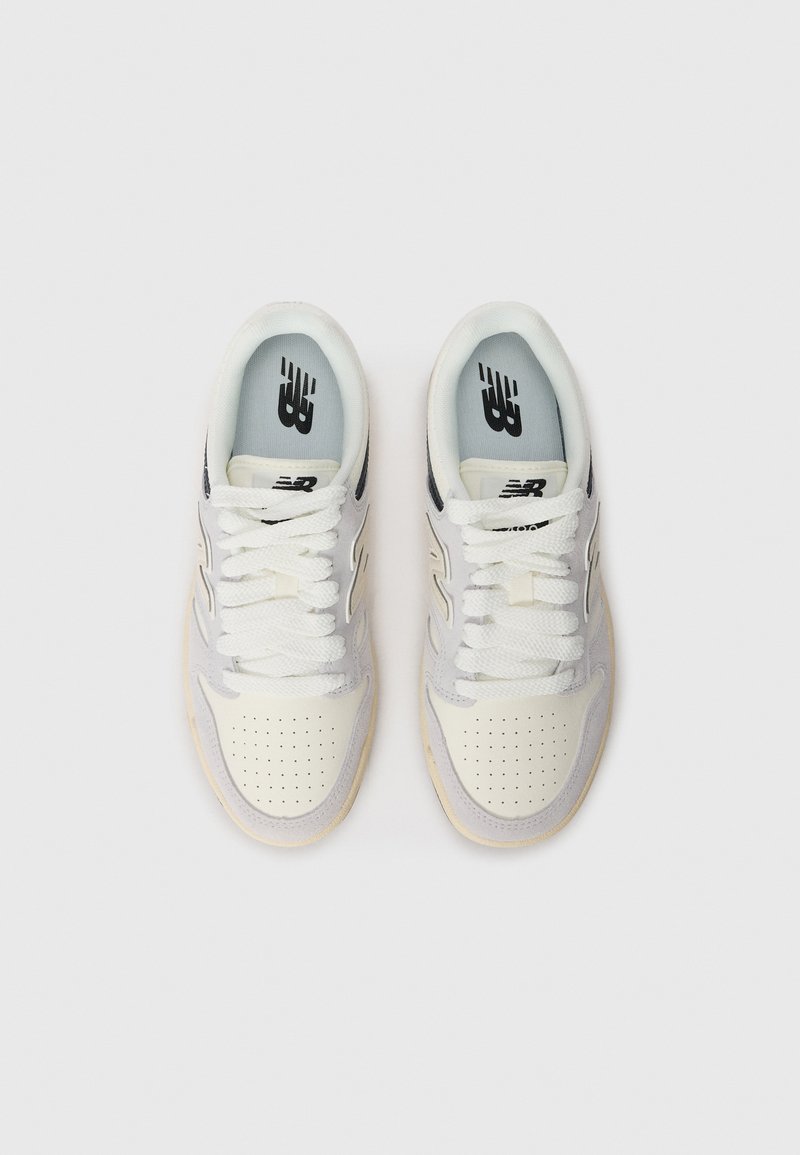 Sneakers bianchi e grigi con punta forata, tomaia testurizzata, lacci piatti e suola in gomma; con logo nero sulla soletta.