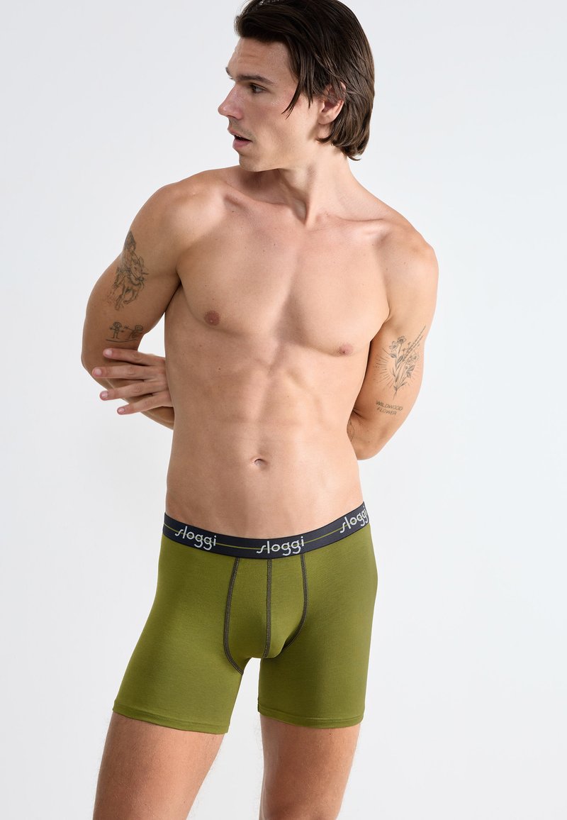 Boxer in cotone verde con elastico nero in vita che presenta il logo "sloggi". Il design è aderente, liscio e senza cuciture, senza motivi visibili.
