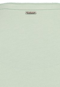 Top de punto verde claro con una textura suave, que presenta un sutil patrón horizontal y una etiqueta plateada con el logo "Key Largo" cerca del escote.