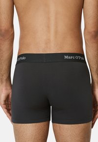 Boxer neri in cotone con una superficie liscia. Presentano un cinturino elastico con marchio con la scritta "Marc O'Polo" in lettere bianche.