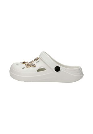 Sabot blanc à enfiler avec des trous de ventilation et des breloques dorées en forme de papillon attachées sur le dessus, avec un bouton noir sur la bride de talon réglable.