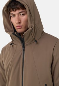 Veste à capuche marron avec une texture lisse, dotée d'une fermeture éclair, de cordons de serrage et d'un design épuré.